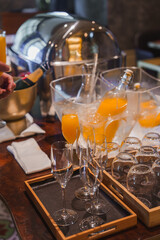 Elegant breakfast or brunch setup featuring orange juice and champagne bottles in a luxury hotel. Includes polished wooden table, elegant glassware, and refined interior design.