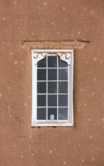 Snow and a Candle in Window in Adobe Wall