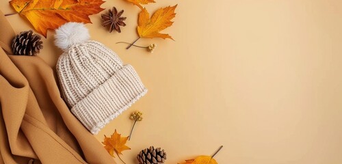 Cozy Autumn Decor With Leaves, Pumpkin, and Knit Hat on Yellow Background