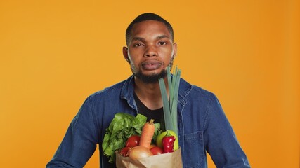 Young adult pretending to lift weight with a paper bag full of bio groceries, mimicking workout...