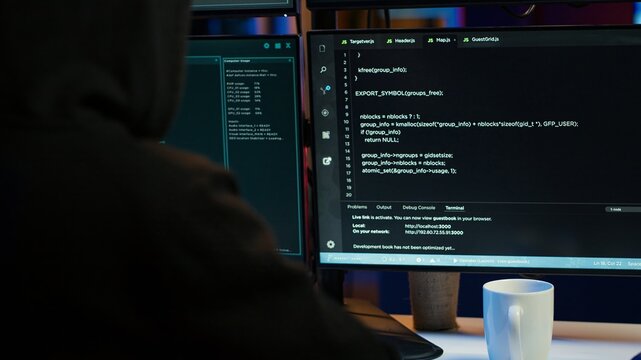 Cybercriminal coding, developing zero day exploit undetectable by antivirus software installed on systems, close up shot. Hooded developer building script able to trick firewalls, camera A