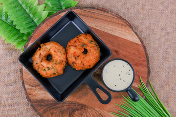 Medhu Vadai is a traditional South Indian delicacy known for its exquisite taste and crispy texture. Vadai, medu vada, uzhunnu Vada, black lentil fritters with coconut chutney on plate served hot.