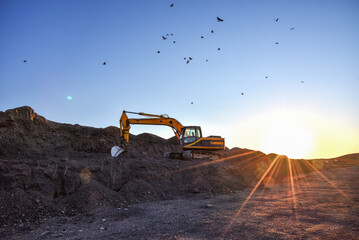 Excavator on sunset background. Open-pit mining. Backhoe dig ground in quarry. Heavy construction...