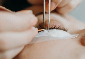 Portrait of a girl cosmetologist extending eyelashes to a woman.