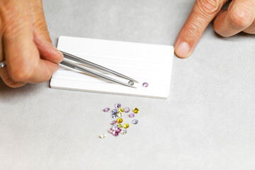 multi-colored sapphires. Gems. A jeweler selects precious stones using a tool. View from above. Macro photography.