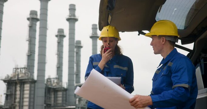 Site engineer team discussing job with blueprint and tablet  at the rear tailgate of vehicle  the trunk of the car 