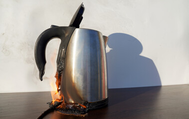 Burning Electric kettle. Electric kettle for tea caught on fire over table. Electric kettle melted...