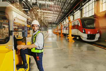 Male worker wearing safety suit during work driving yellow locomotive for towing  standing reporting with walkie talkie in building electric train station electric tram transportation system.
