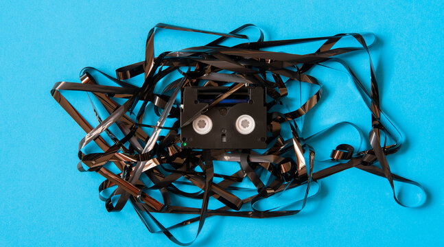 Old black mini DV cassette with tangled tape surrounding the cassette