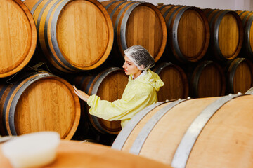 Female wine production supervisors wear robes and head nets inspecting the storage neatness ...