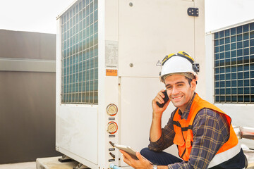 Male HAVC refrigeration engineer reporting by radio inspecting refrigeration equipment on building rooftop care equipment hot coil panels ventilation fans check performance and damage.