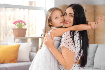 Happy mother with her little daughter hugging at home