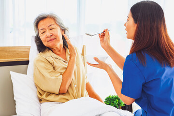 Sick elderly woman uses her hands refuse eat porridge that female nurse tries feed her breakfast...