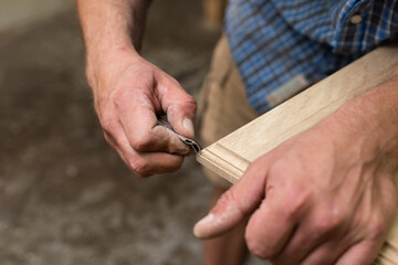 The carpenter manually sanded the corner of the oak panel with sandpaper
