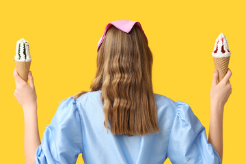 Young woman holding ice creams in waffle cone on yellow background, back view