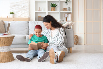 Little African-American boy with his mother reading book at home
