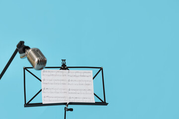 Stand with notes and microphone on blue background