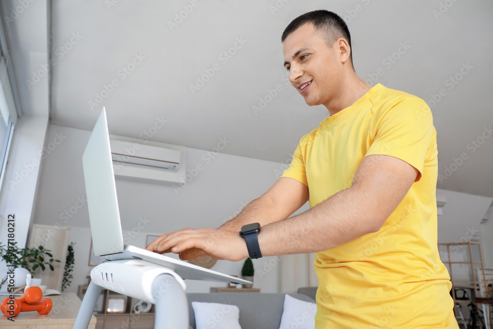 Canvas Prints sporty young man with laptop training on treadmill at home