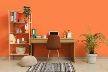 Comfortable workspace with modern laptop near orange wall