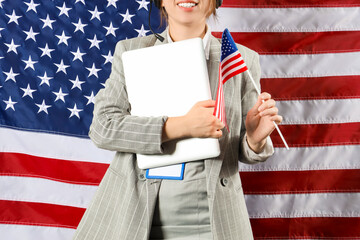 Young female tech support agent with laptop standing against USA flag