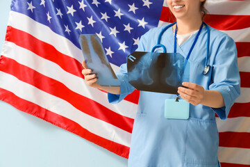 Young female doctor with x-ray images and USA flag on blue background