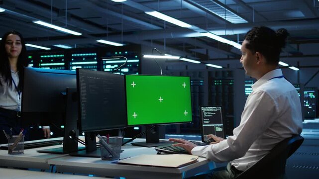 Engineer in data center monitoring security threats using mockup computer, implementing cybersecurity measures. Man using green screen PC, ensuring compliance with regulations, camera B