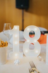 Table decoration with the illuminated number 18 for a celebration event.