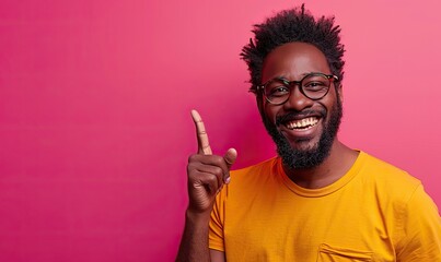 An excited man with glasses, pointing to the side against a lively pink background, showcases his enthusiasm and joy.