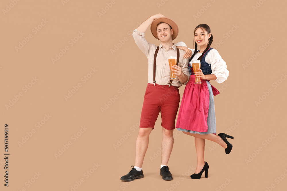 Sticker young happy couple in traditional german clothes with glasses of beer on beige background