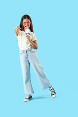 Little girl with microphone singing on blue background