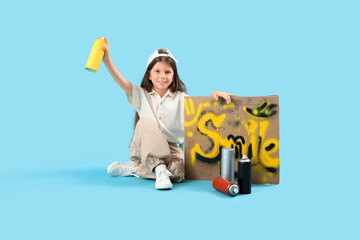 Little girl with spray paint cans and graffiti sitting on blue background
