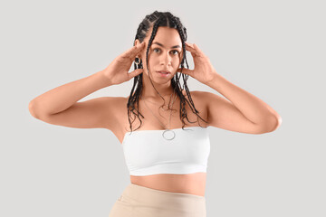 Young African-American woman with dreadlocks on light background