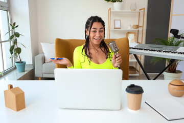 Young African-American woman with microphone recording podcast in studio