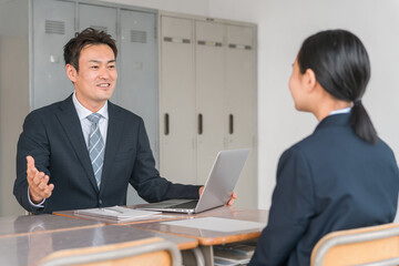 面談・進路相談・二者面談をする男性教師とブレザー姿の女子中学生
