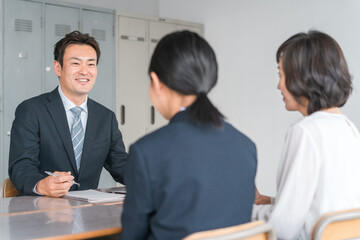 笑顔で三者面談を受ける親子と先生（中学生・高校生）
