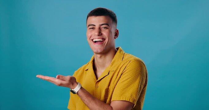 Hand, face or happy man with palm for space in studio for news, presentation or deal offer on blue background. Smile, portrait and model showing promo, launch or mockup for coming soon announcement