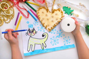 Child making a greeting card, New Year decorations and funny sketch.  Craft for children. Nice greeting card, golden heart. Top view