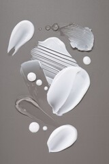 Face cream and gel on grey background, top view
