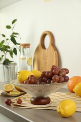 Fruit vase with grapes and lemon on wooden countertop in kitchen