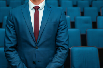 Professional man in a blue suit standing confidently in an empty conference hall, showcasing business attire and leadership.