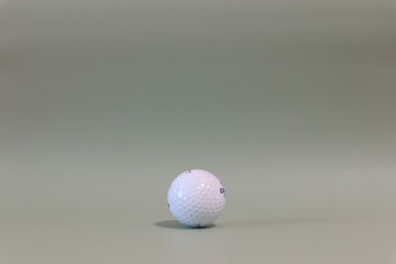 Isolated photo of a golf ball on a turquoise green background