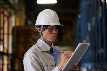 工場内で点検を行う作業着を着た男性