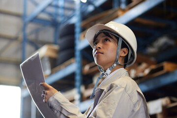 工場内で点検を行う作業着を着た女性