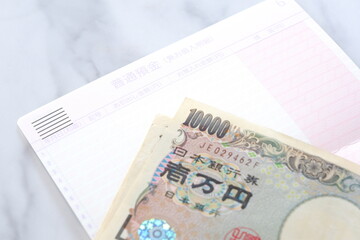 テーブルの上に開いた状態で置かれた銀行の預金通帳と、1万円札
