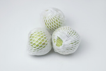 The green guava fruit is covered plastic is on a white background