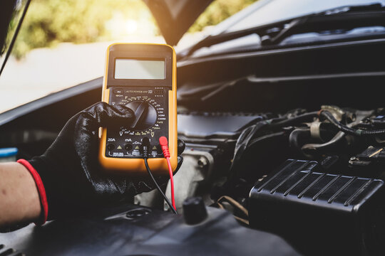 Car mechanic use voltmeter to check voltage battery low energy problem for car care service maintenance and re charger or jump start or change battery replacement.