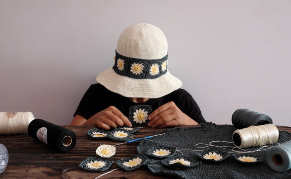 Woman wear daisy motifs crohet hat, surrounded by an array of colorful supplies materials for diy project, leisure with creativity handmade in workspace
