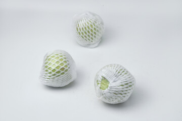 The green guava fruit is covered plastic is on a white background