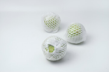 The green guava fruit is covered plastic is on a white background
