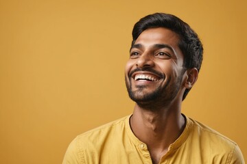 Obraz premium Happy joyful smiling young indian man looking aside up standing isolated on yellow background. Portrait